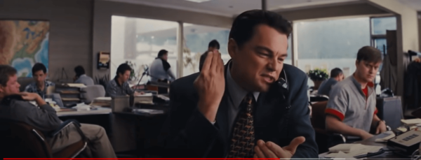 a white make wearing suit and tie speaking firmly over the telephone